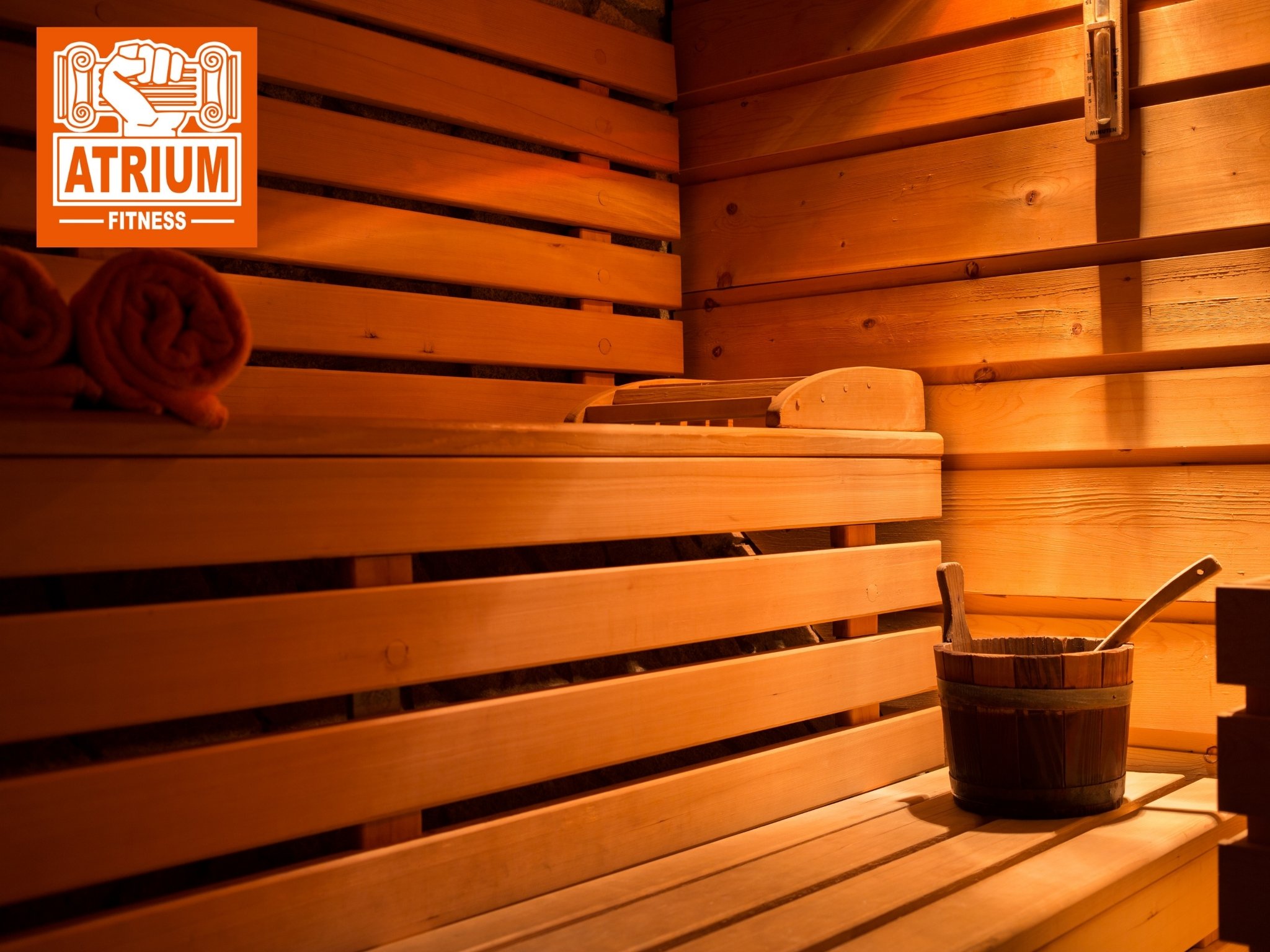 Eine leere Sauna aus hellem Holz mit einem Eimer und Schöpfkelle.